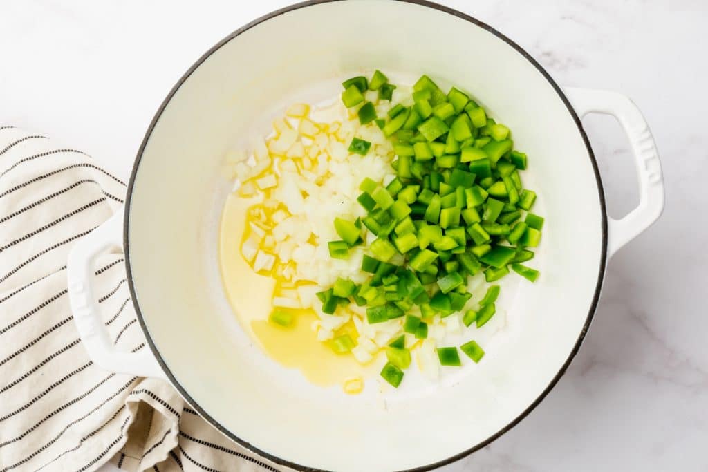 diced onions and green bell pepper in a white dutch oven