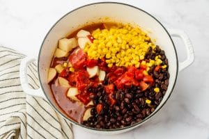 vegetable stock, red potatoes, black beans, corn, and diced tomatoes in white dutch oven