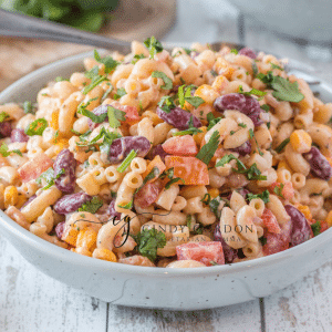 creamy macaroni salad with red, purple and green vegetables in it in a blue bowl