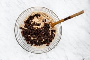 bowl full of flour raisins and oats with wooden spoon
