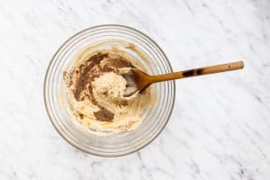 creamed butter with brown sugar in a clear bowl with wooden spoon