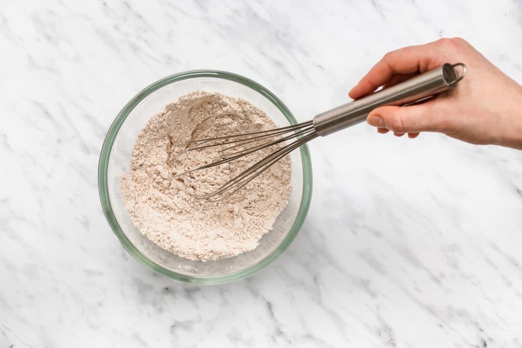 clear bowl with flour like substance with metal whisk