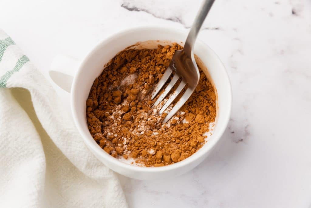 white bowl with brown crumble mixture and fork