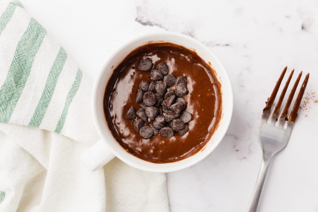 white bowl with vegan brownie mug cooked and chocolate chips on top
