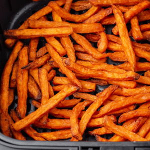 bright orange cooked sweet potato fries in black air fryer basket