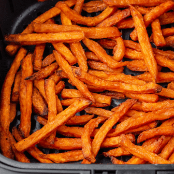 bright orange cooked sweet potato fries in black air fryer basket