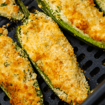black air fryer basket with golden brown air fried jalapeno poppers