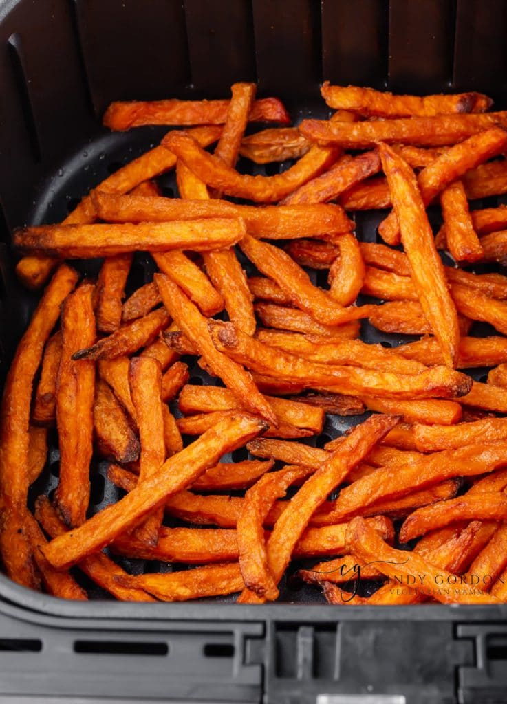 bright orange cooked sweet potato fries in black air fryer basket