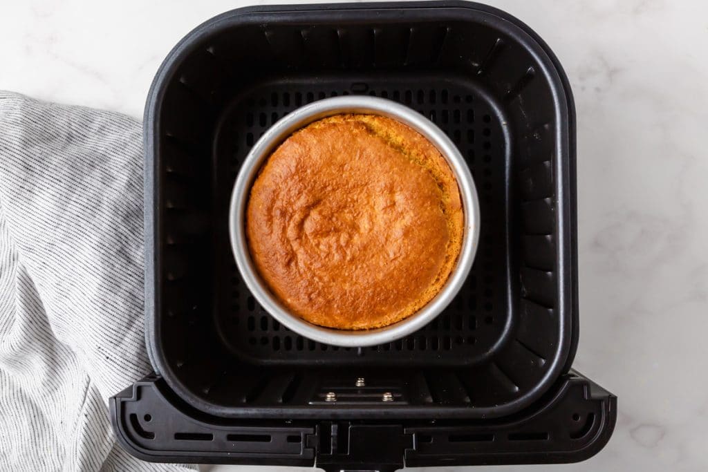 golden brown air fryer cornbread in a silver metal round container in a black air fryer basket