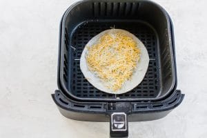 Air Fryer Quesadilla with cheese showing in a black air fryer basket