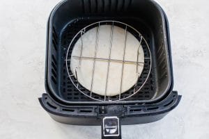 Air Fryer Quesadilla in a black air fryer basket with metal trivet over top