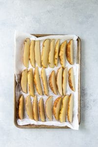 cut air fryer potato wedges on a white paper towel in a lipped baking sheet