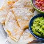 Air Fryer Quesadilla on white plate with guac in a blue bowl and red salsa in a green bowl