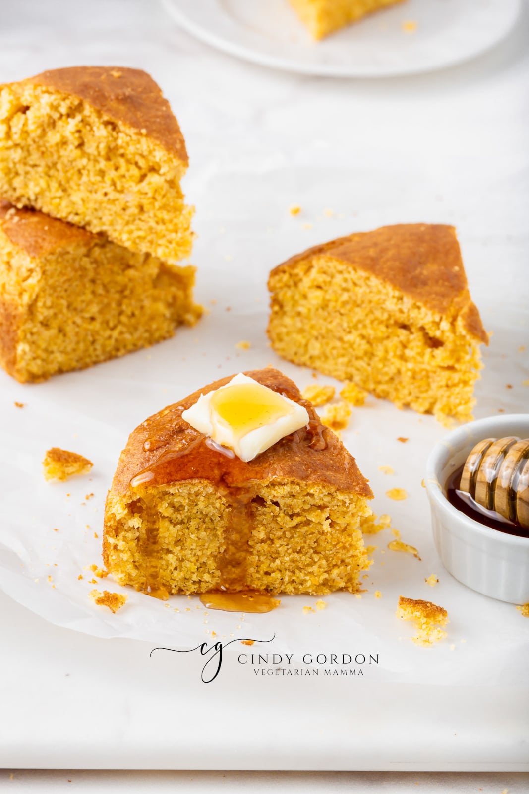 golden brown slices of air fryer cornbread with a square pad of white butter on top and honey dripping down the sides