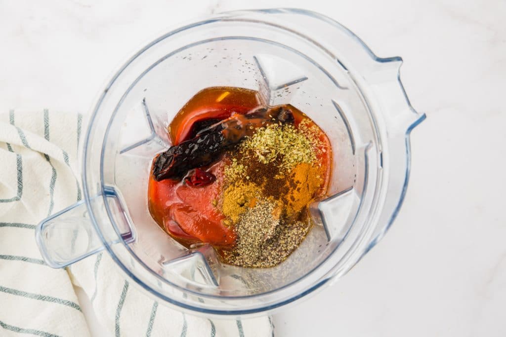 red liquid and spices in clear blender