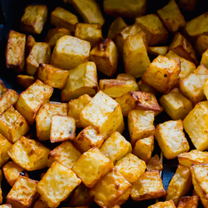 crispy brown cubed potatoes in a black air fryer basket