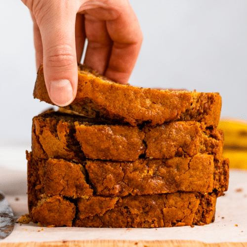 brown bread stacked up with a hand grabbing the top piece