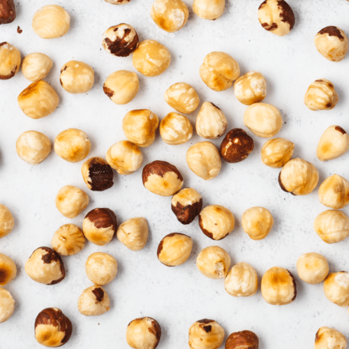 roasted hazelnuts on a white background, some skins removed