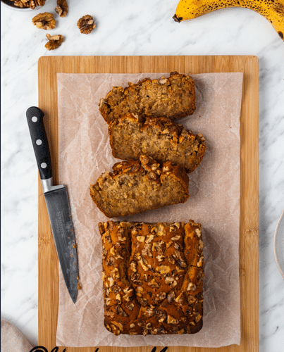 Sliced banana bread on cutting board with a knife.