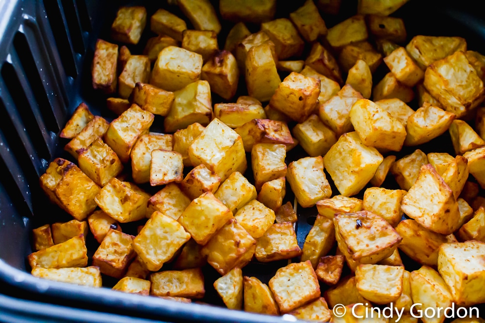 crispy brown cubed potatoes in a black air fryer basket