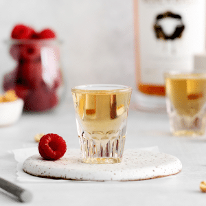 peanut butter and jelly shot in a shot glass. fresh raspberries are in the background.