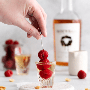 a PBJ shot with a skewer of fresh raspberries in it.