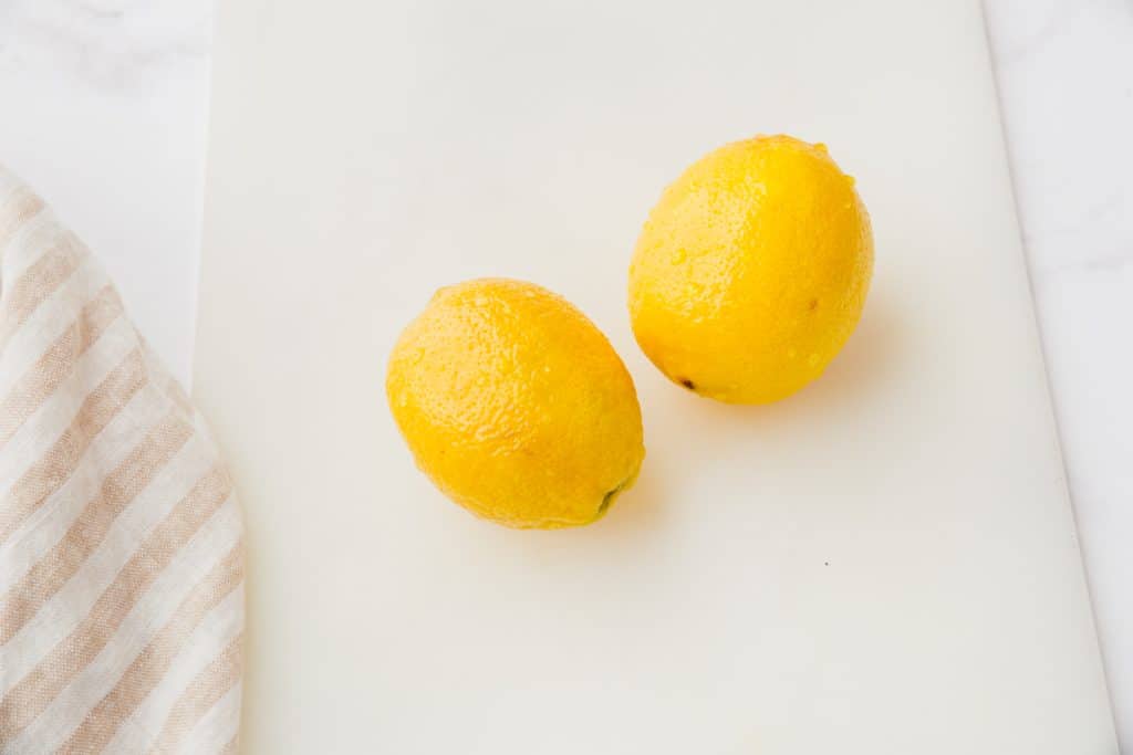 two lemons on white cutting board