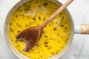 yellow liquid mixture in pot with wooden spoon