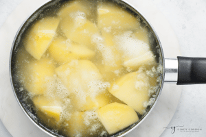 water in pot with yellow potato cubes