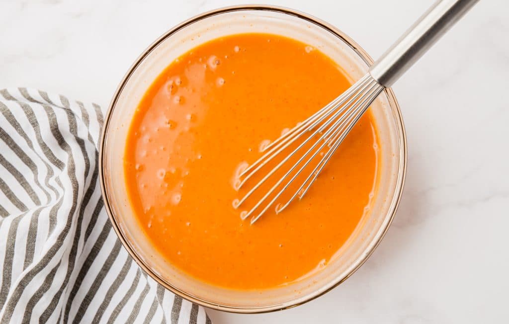 Sweet and Spicy Sriracha Sauce mixed in clear bowl with whisk