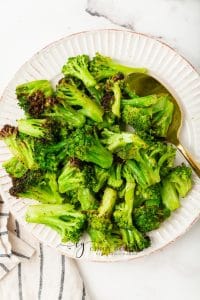 air fryer frozen broccoli served on a white plate with a golden spoon