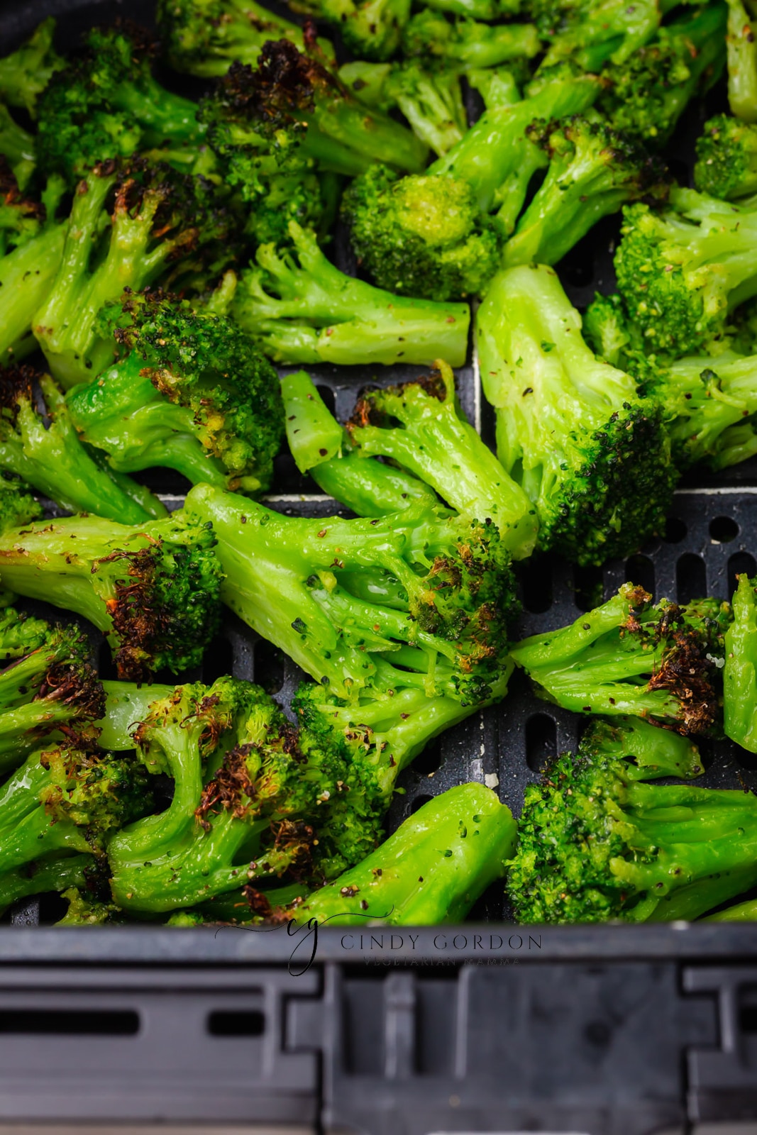 close up of frozen green broccoli in black air fryer basket