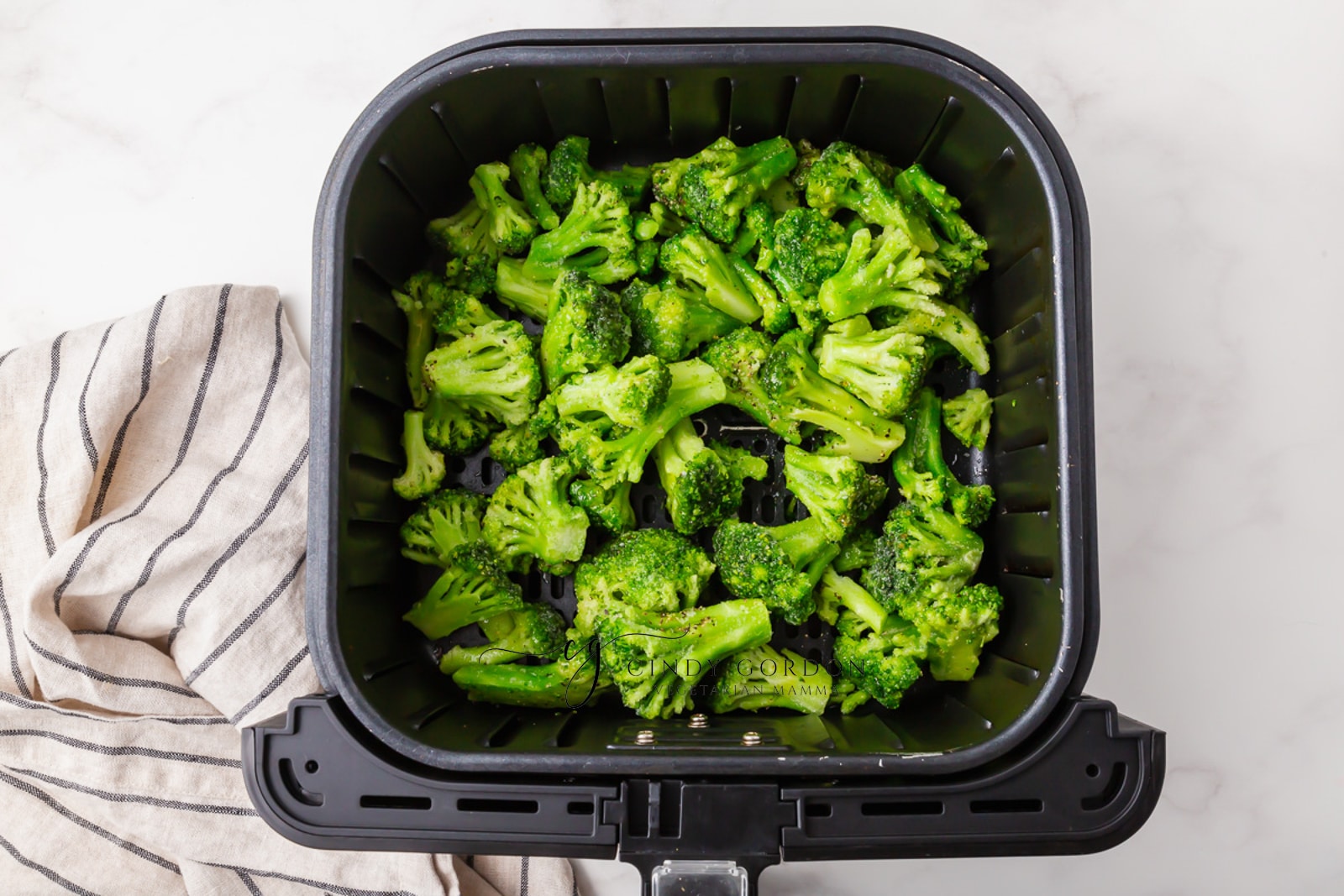 frozen green broccoli in black air fryer basket