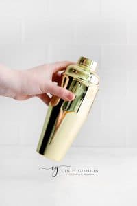 hand holding gold cocktail shaker