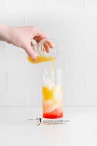 clear glass with ice, red liquid and orange liquid