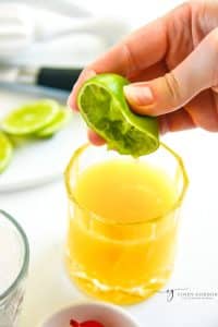 a half lime squeezed into a rocks glass with orange juice and rum