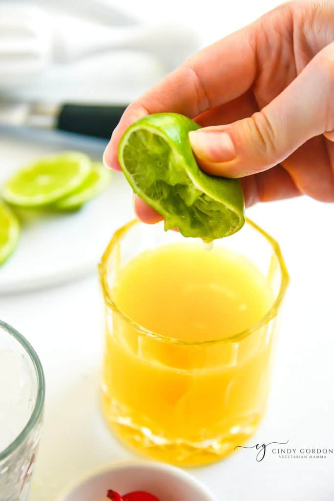 a half lime squeezed into a rocks glass with orange juice and rum