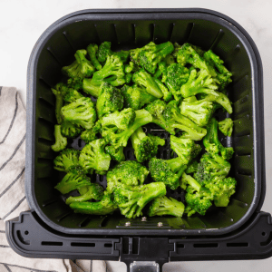 frozen green broccoli in black air fryer basket