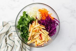 ingredients for kale apple slaw in a glass bowl