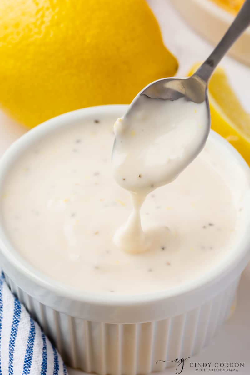 A small spoon stirring a cup of homemade lemon garlic mayo