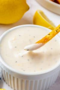 a french fry being dipped into a ramekin filled with homemade lemon garlic aioli