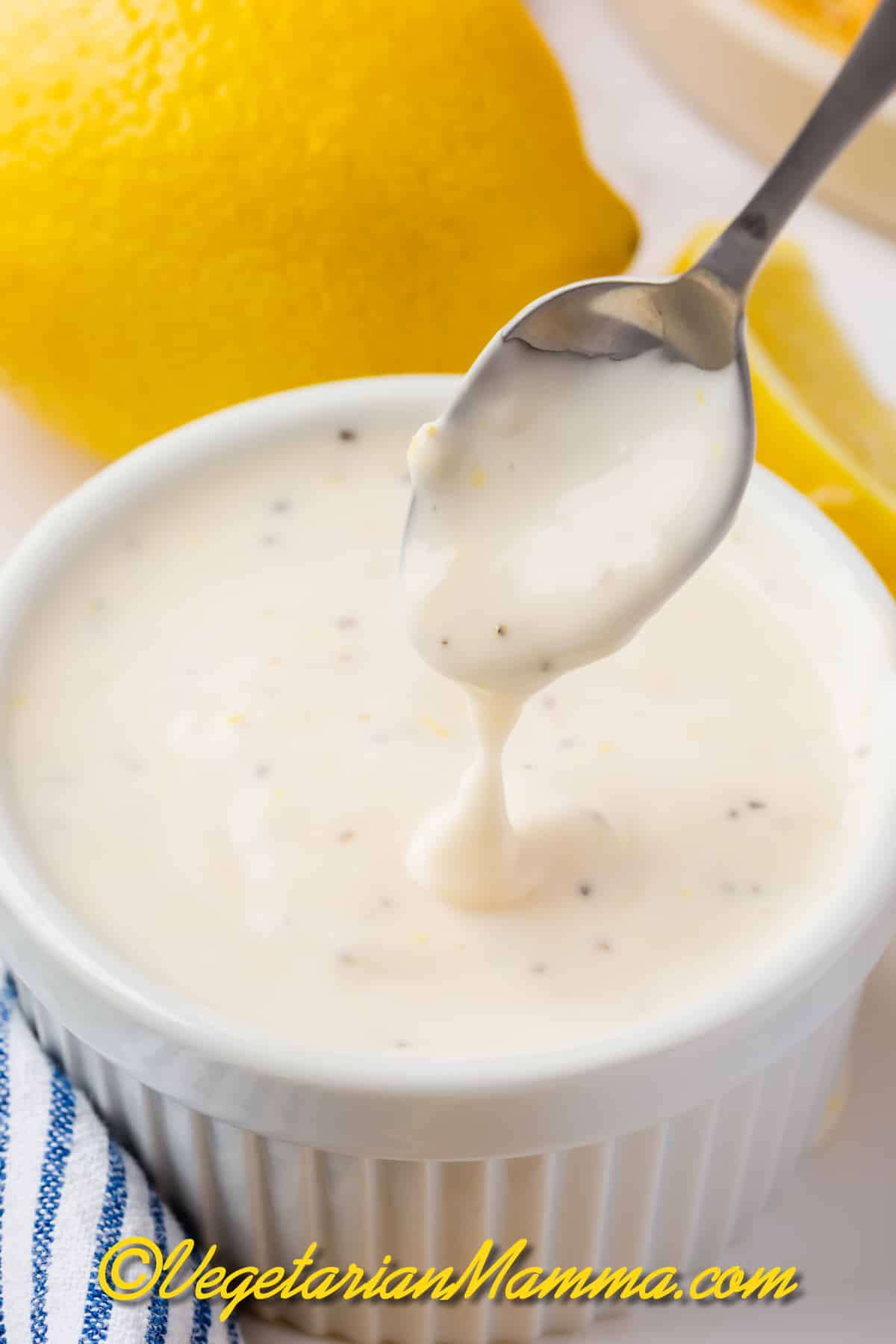 A small spoon stirring a cup of homemade lemon garlic mayo