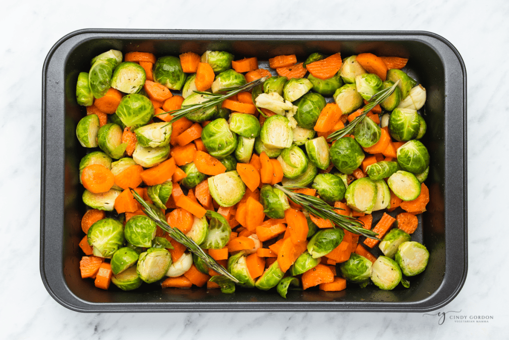 a mix of brussel sprouts and carrots in a roasting pan