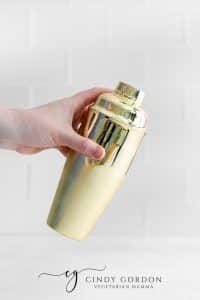 hand holding a gold drink shaker
