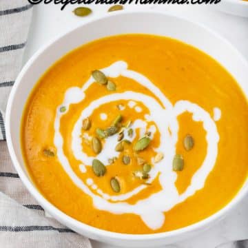 pumpkin bisque in a white bowl with white sauce drizzled on top