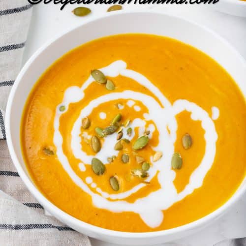 pumpkin bisque in a white bowl with white sauce drizzled on top