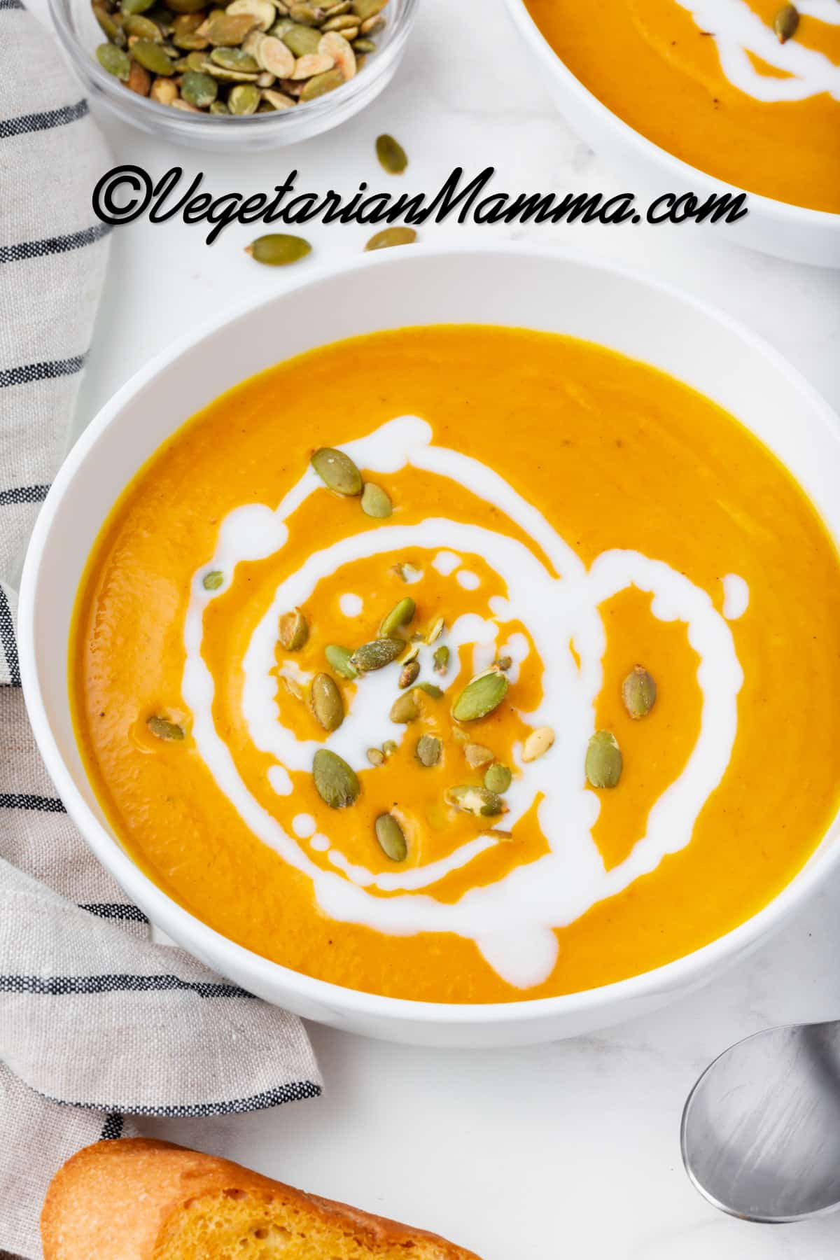 pumpkin bisque in a white bowl with white sauce drizzled on top