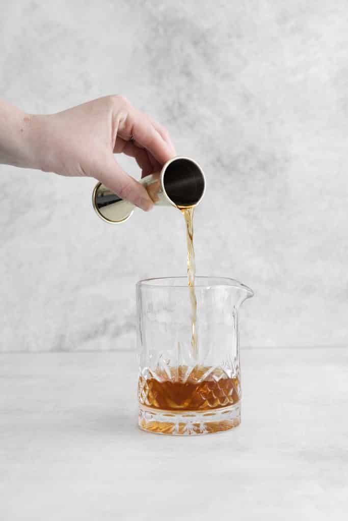 Hand pouring brown liquid into glass