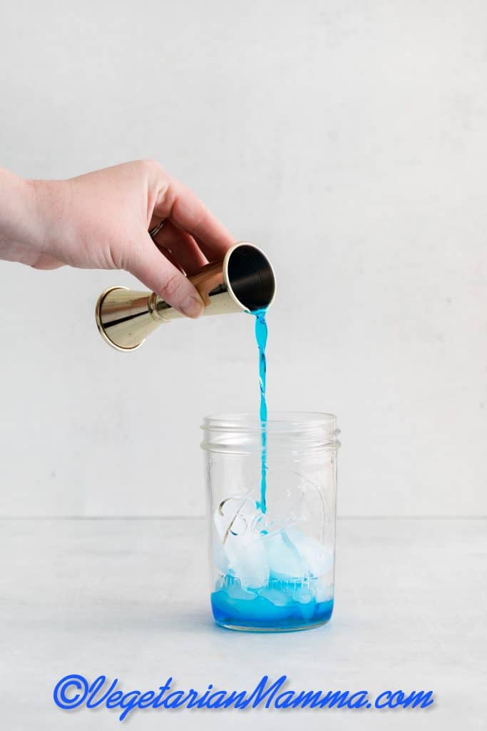 Fill a cocktail shaker with ice and add the blue curacao, gin, vodka, tequila, rum, lemon juice, and simple syrup.