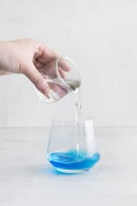 clear liquid being pourn into a glass with blue liquid